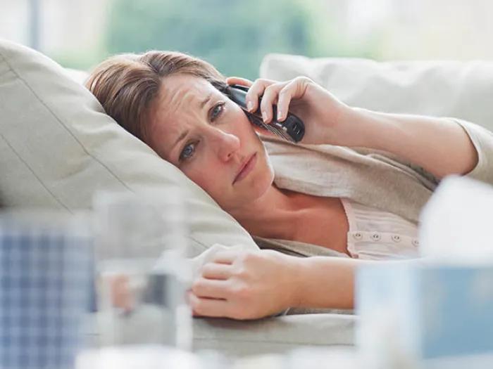 woman sick on couch on phone