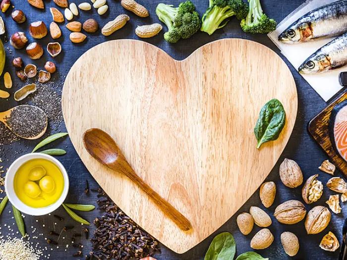 Heart shaped cutting board with wooden spoon and food around