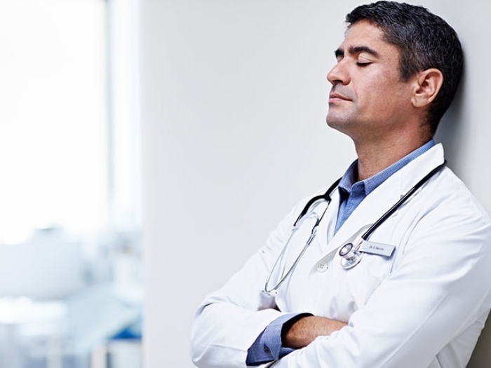 internist closing eyes and leaning against wall