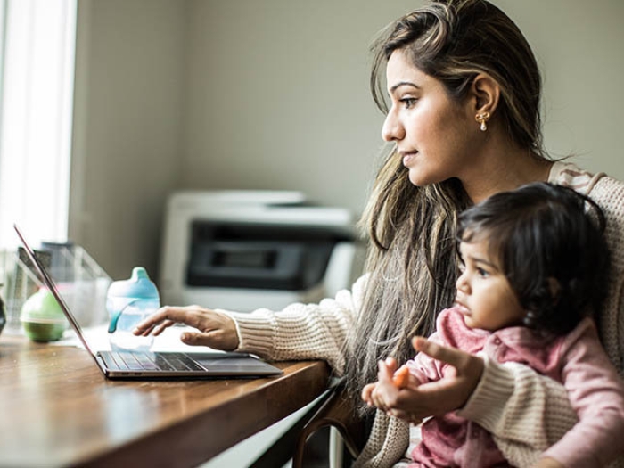 mom working on laptop with child on lap at table