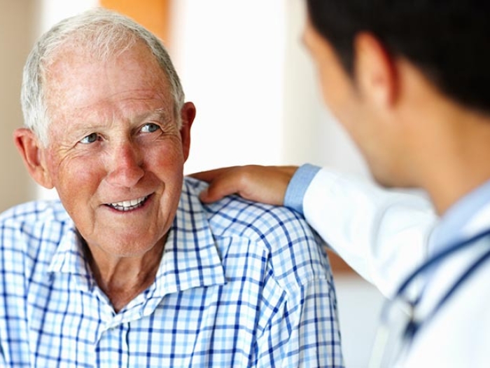 older gentleman in blue checkered shirt talking with doctor