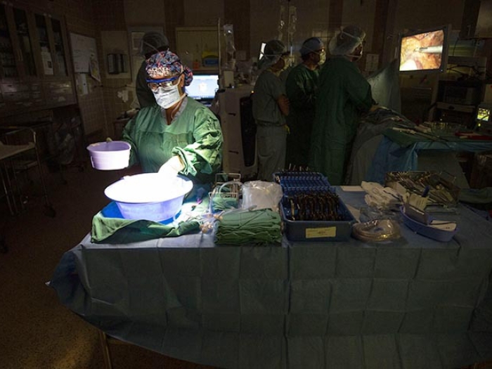 surgeon in dark operating room with light shone on them