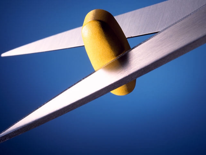 Scissors cutting a pill in half