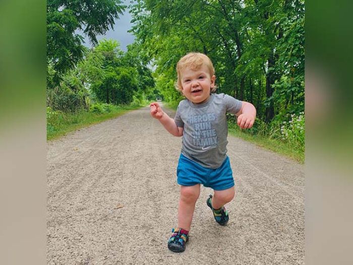 Toddler walking on dirt path surrounded by trees