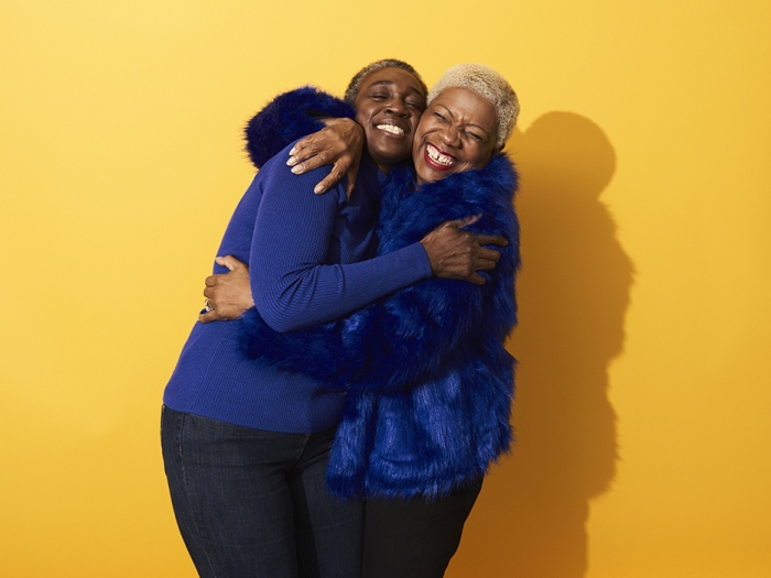 two adults hugging in yellow background wearing royal blue clothes