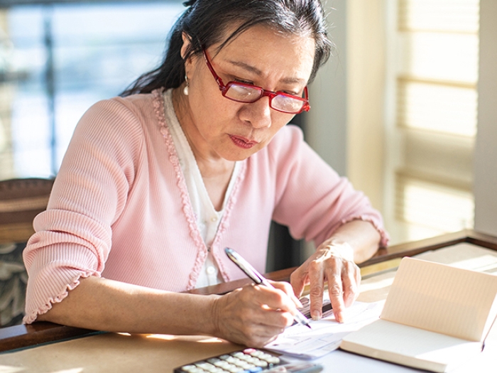 woman doing bills in living room with pink shirt and red glasses on