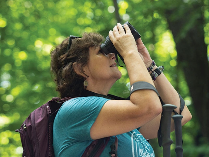 woman in forest looking with binoculars