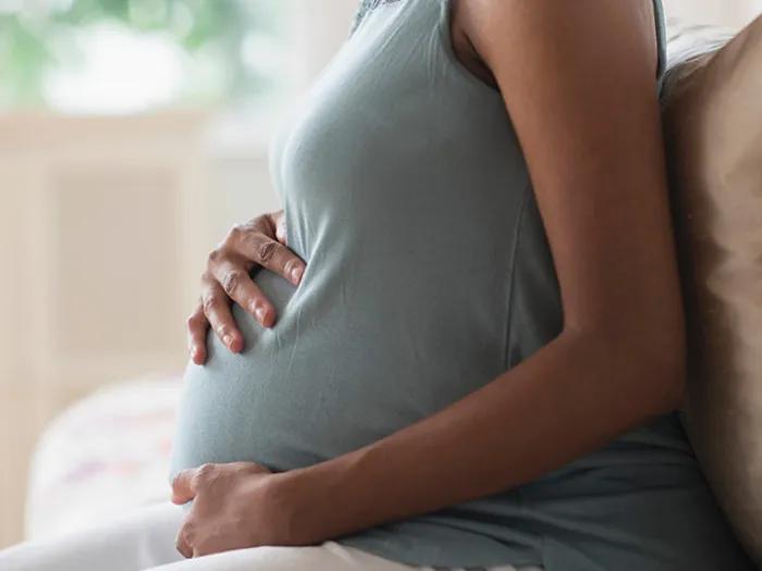 person pregnant holding stomach green shirt sleeveless