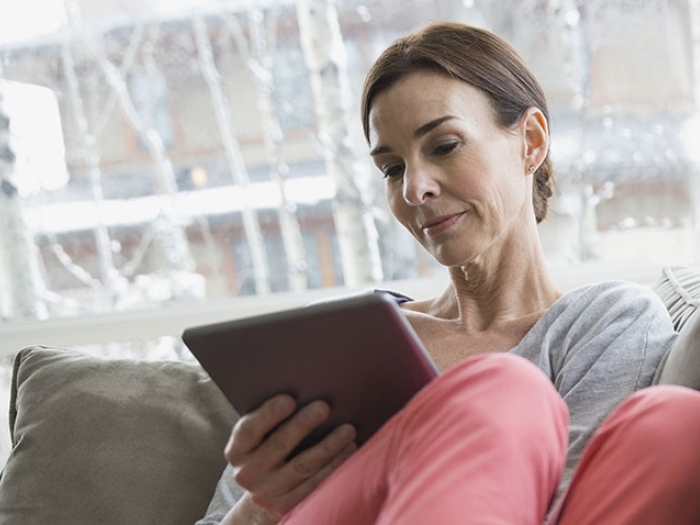 Woman sitting on a sofa reading from an ipad