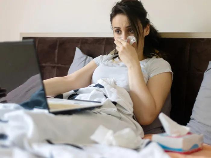 woman in bed blowing nose
