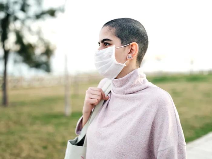 woman standing mask in pink shirt outside