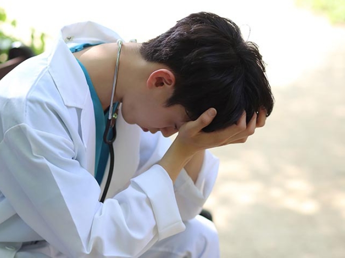 young doctor stressed on park bench