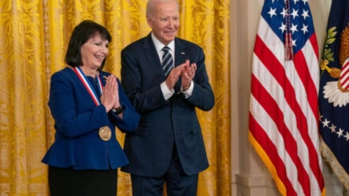 Huda Akil, PhD wearing blue suit jacket with peplum waist and National Medal of Science with President Biden and American flag