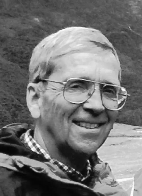 Black and white headshot of Kurt Seiffert. He's wearing glasses and a jacket and is outdoors.