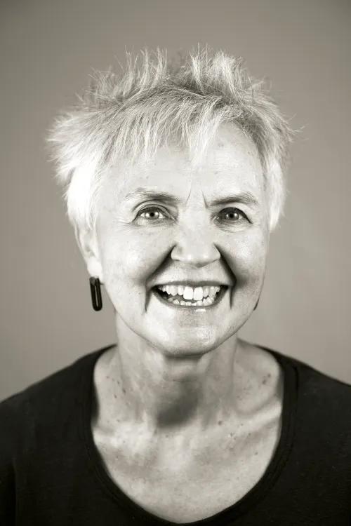 Black and white headshot of Nancy Dodge. She is wearing a black shirt and is looking at the camera and smiling.