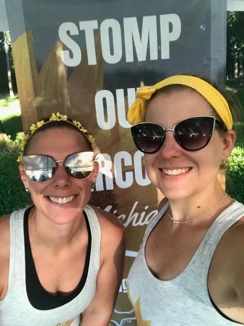 Smiling photo of Maxwell and Privett standing in front of a Stomp Out Sarcoma sign