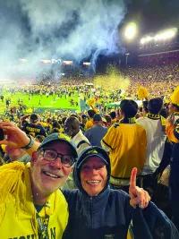 A selfie of two people at a Michigan football game. 