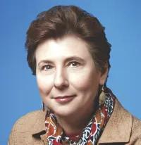 Headshot of Rosalind Wright. She has short brown hair and is wearing a light brown jacket and a floral scarf.