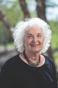 Older woman with short white hair smiling at the camera. 