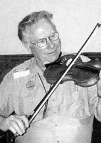 Black and white portrait of George smiling as he plays his fiddle. He has short gray hair and glasses and is wearing a name tag.