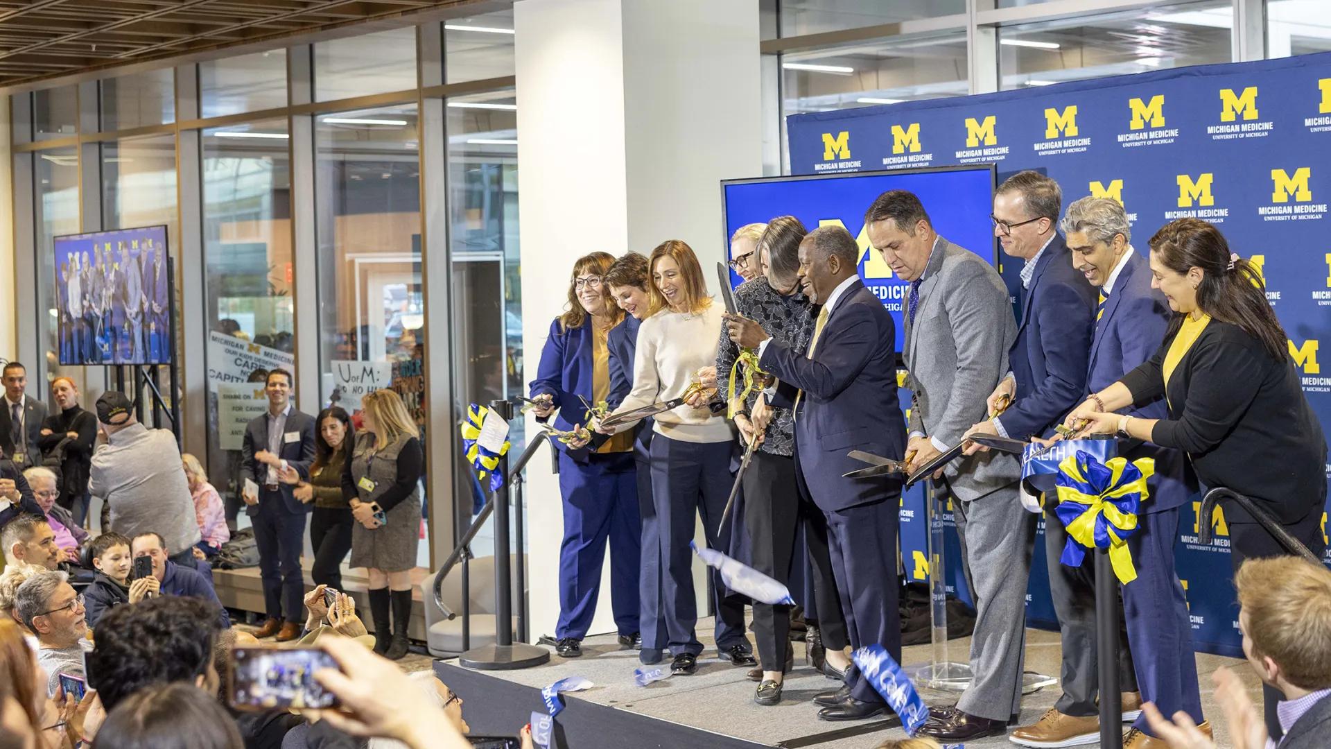 Ribbon cutting at the opening of the Kahn Pavillion. Ten Michigan leaders cut the blue ribbon