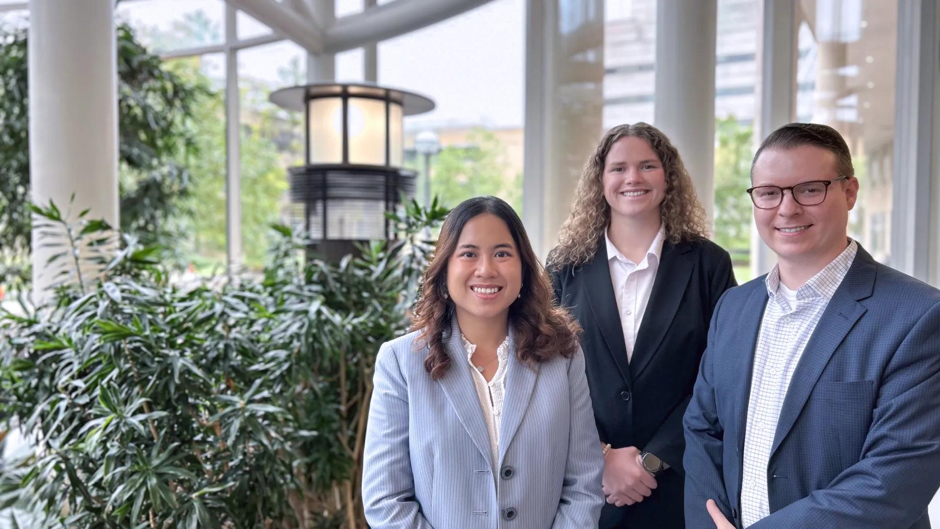 Two women and one man wearing business suits standing in the Frankel Cardiovascuar Center atrium