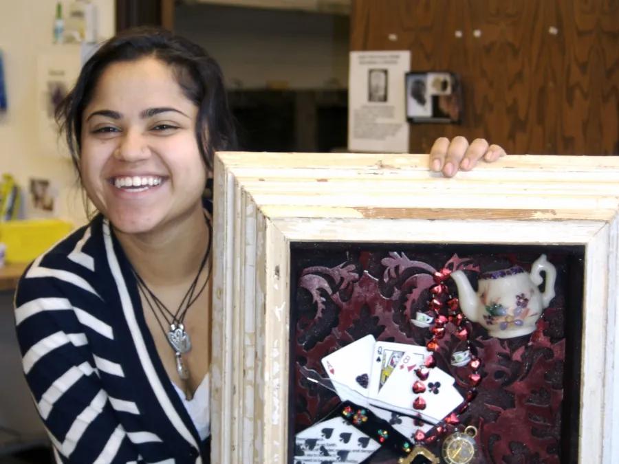 Shali smiles and shows off her art in a box