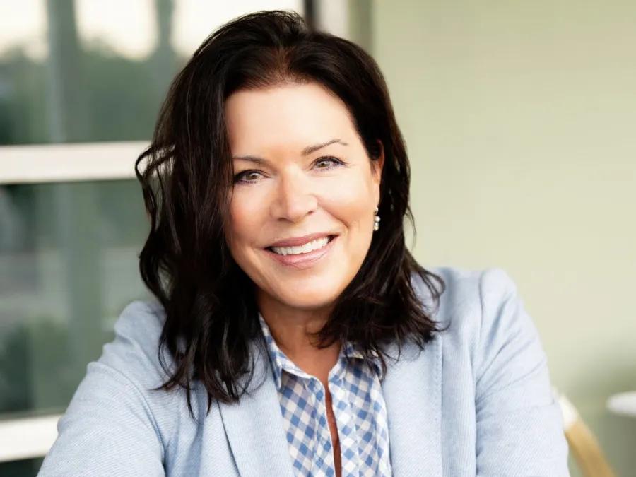 Smiling photo of Donna Murphy. She has medium-length dark hair and is wearing a light blue blazer and patterned blue and white top.