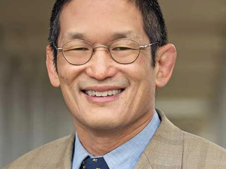 Smiling headshot of Lawrence An, M.D. He's wearing a tan jacket with a blue tie.