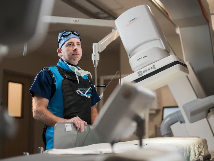 A medical professional stands in front of a piece of medical equipment.