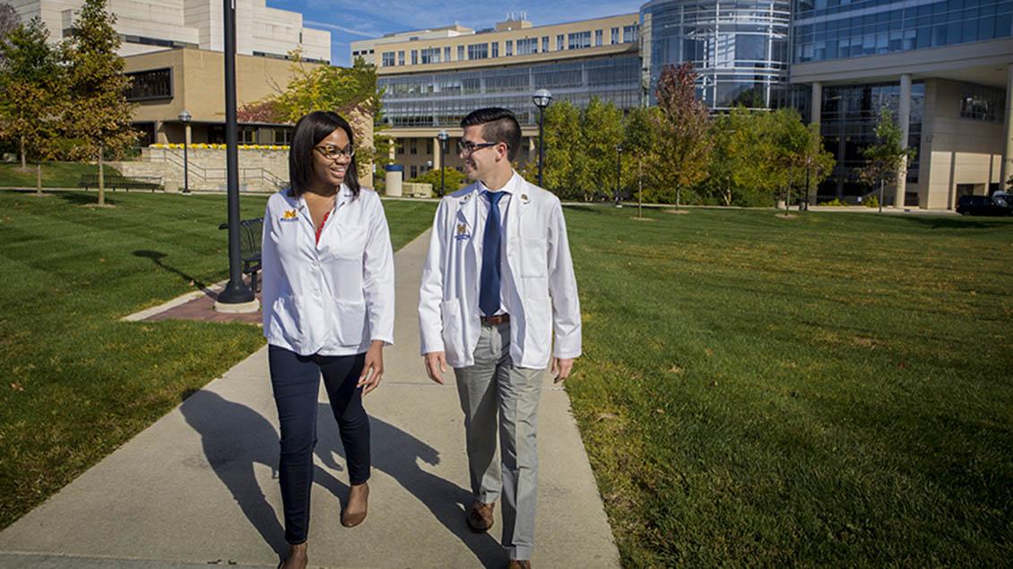 Black female doctor and White male doctor walking together out the U-M Frankel Cardiovascular Center
