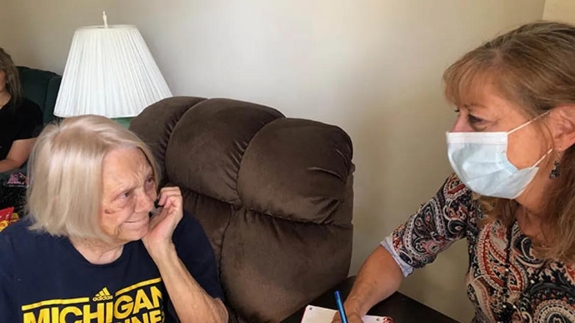 Elderly woman smiling at woman wearing mask.