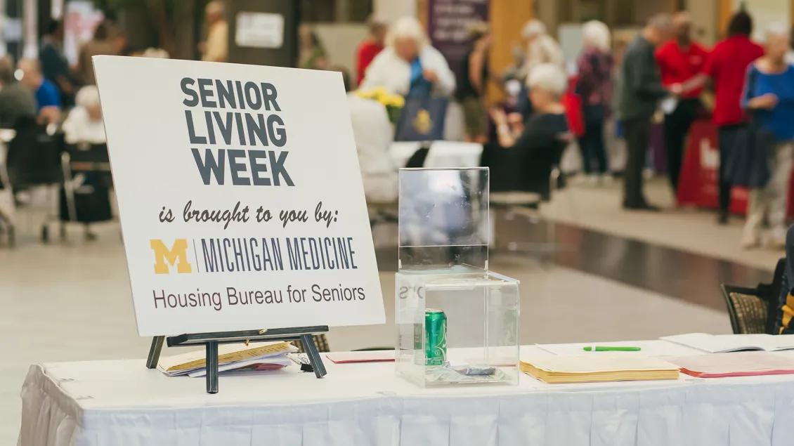 Table at event with sign on easel reading, Senior Living is brought to you by: Michigan Medicine - Housing Bureau for Seniors