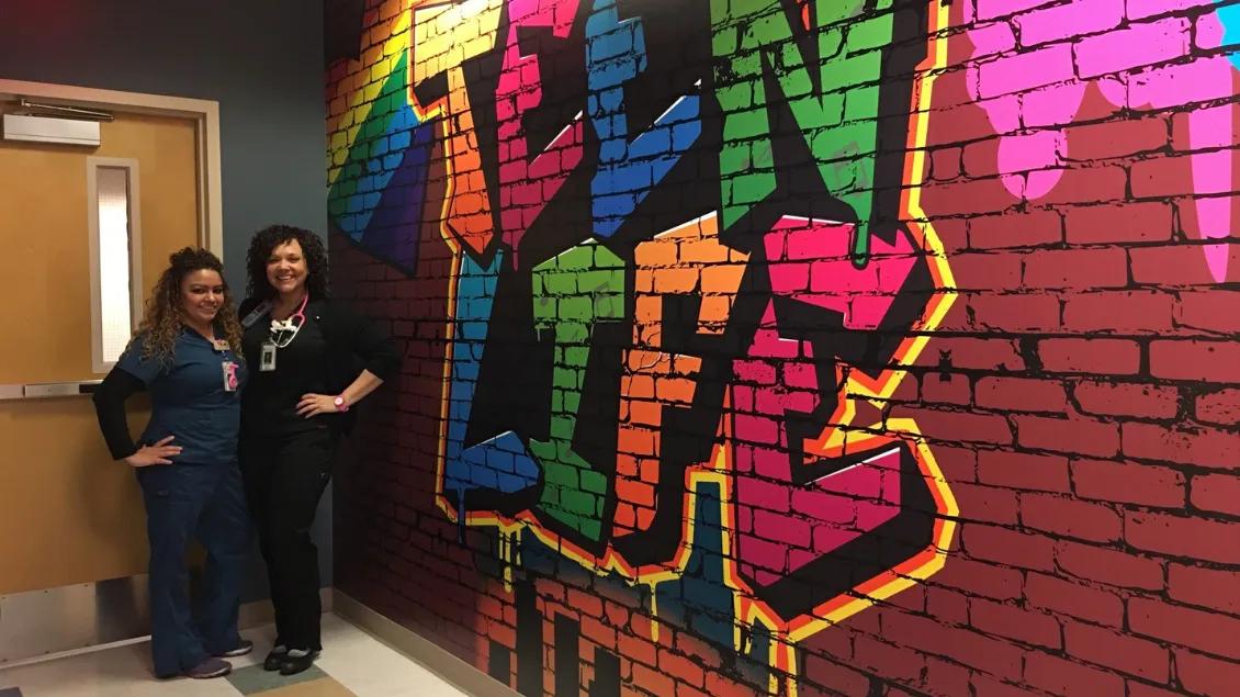 Health care professionals standing in front of a faux graffiti wall in a health center