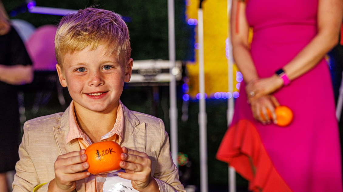 Boy at Event on Main holding a small pumpkin with $20k written on it