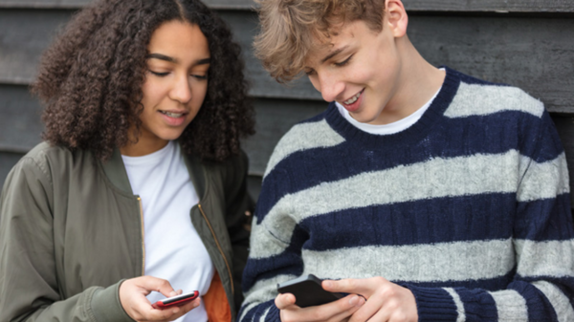 teen girl and boy look at their phones