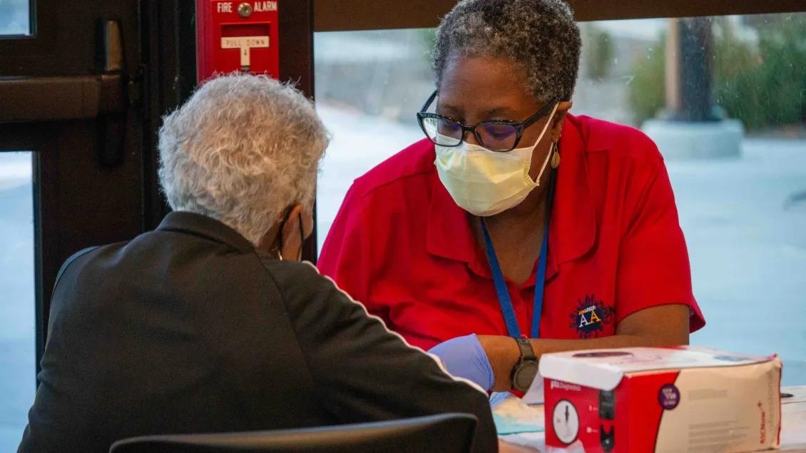 woman helps another woman at vaccine clinic table