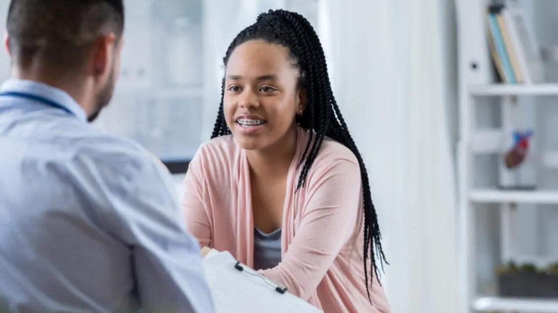 teen girl with braces smiles while talking with staffer