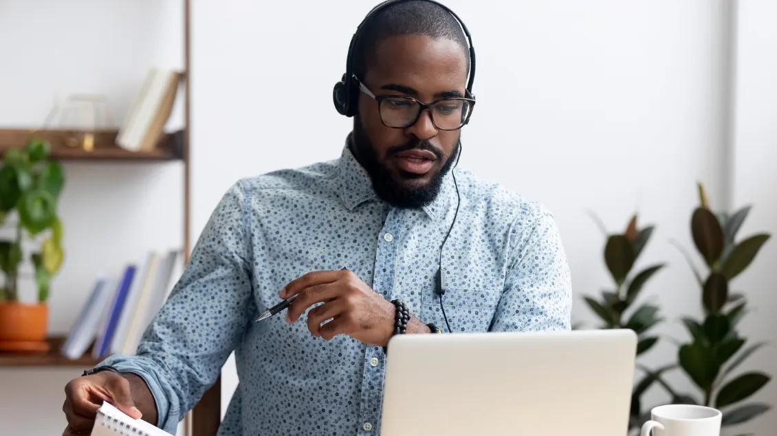Man with headphones looking at the laptop.