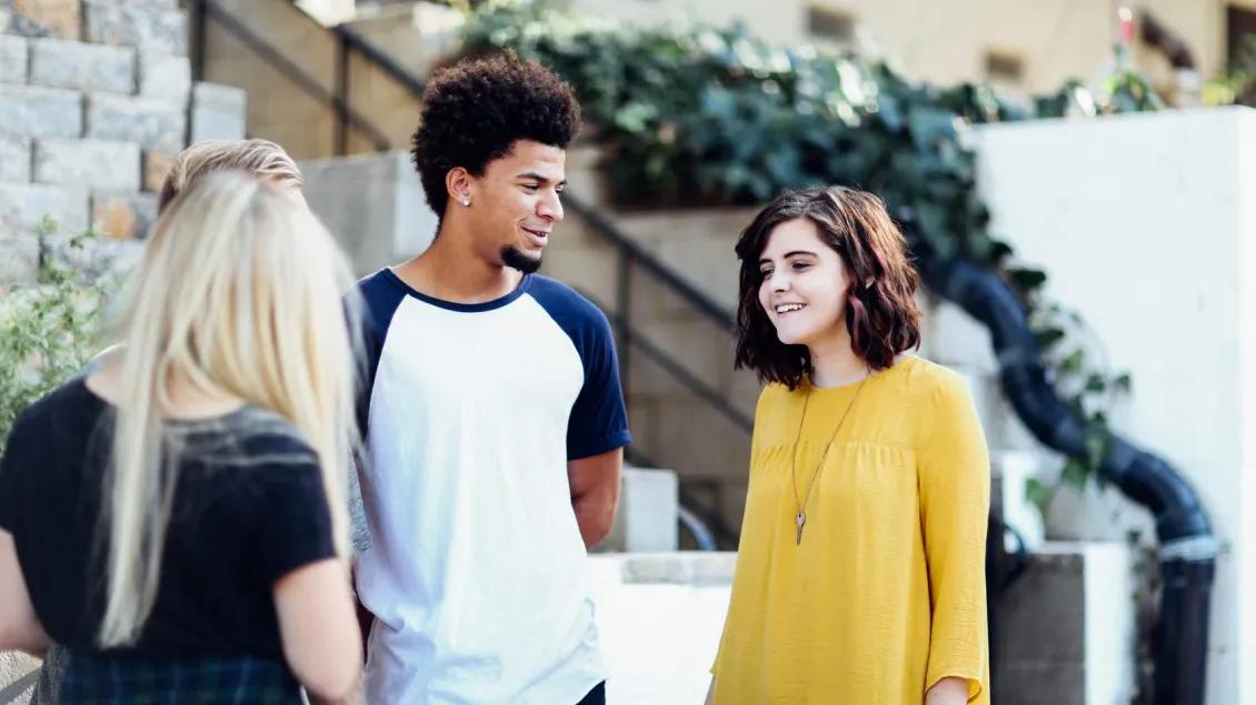 A group of young people smiling and talking to each other.
