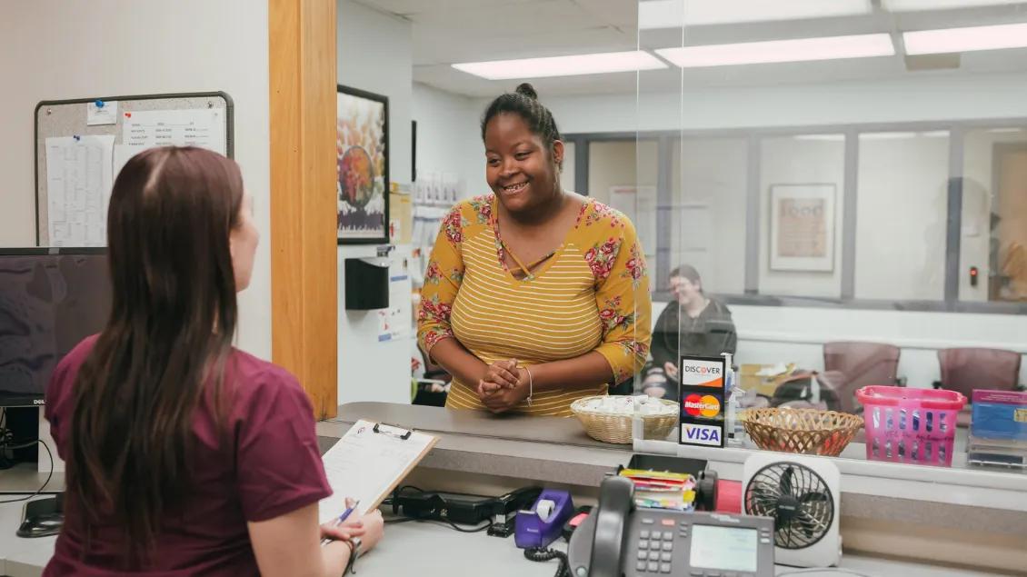 woman stands at health care check-in counter