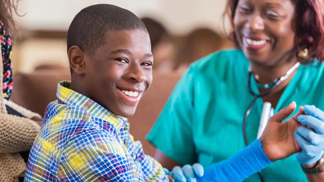 Teen boy smiles at camera while getting health exam