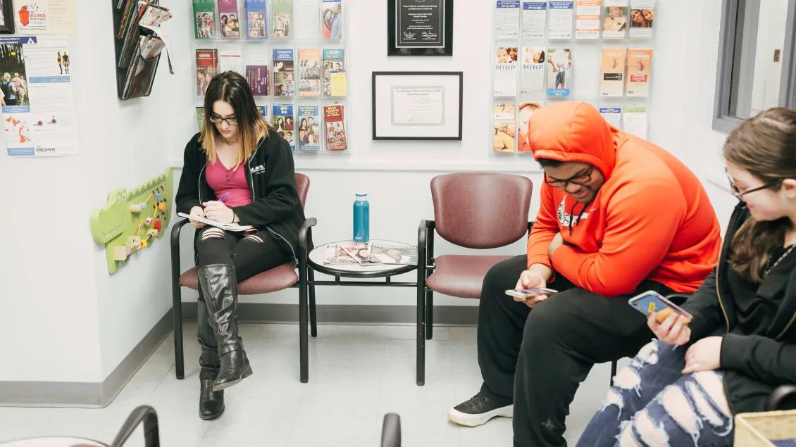 Teens in a health waiting room with posters and certifications on the wall