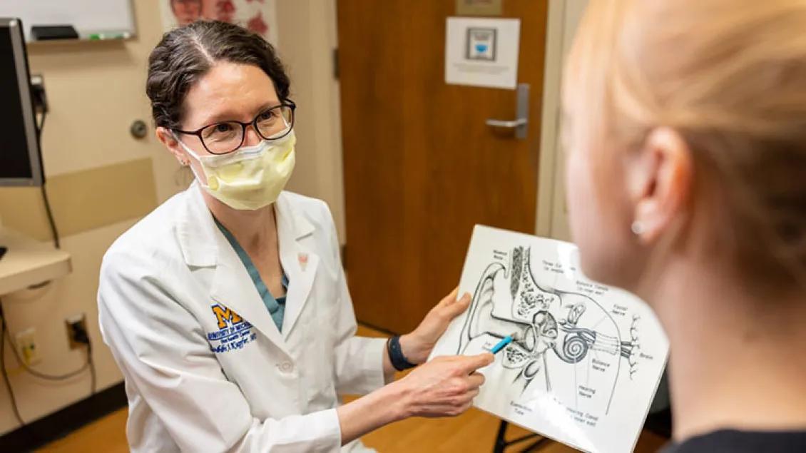 A doctor shows a diagram of the inner ear to a patient.