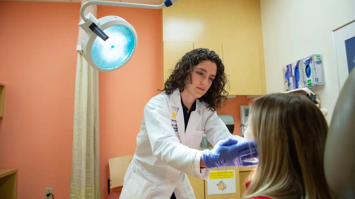 An oral surgeon meets with a patient in an exam room.