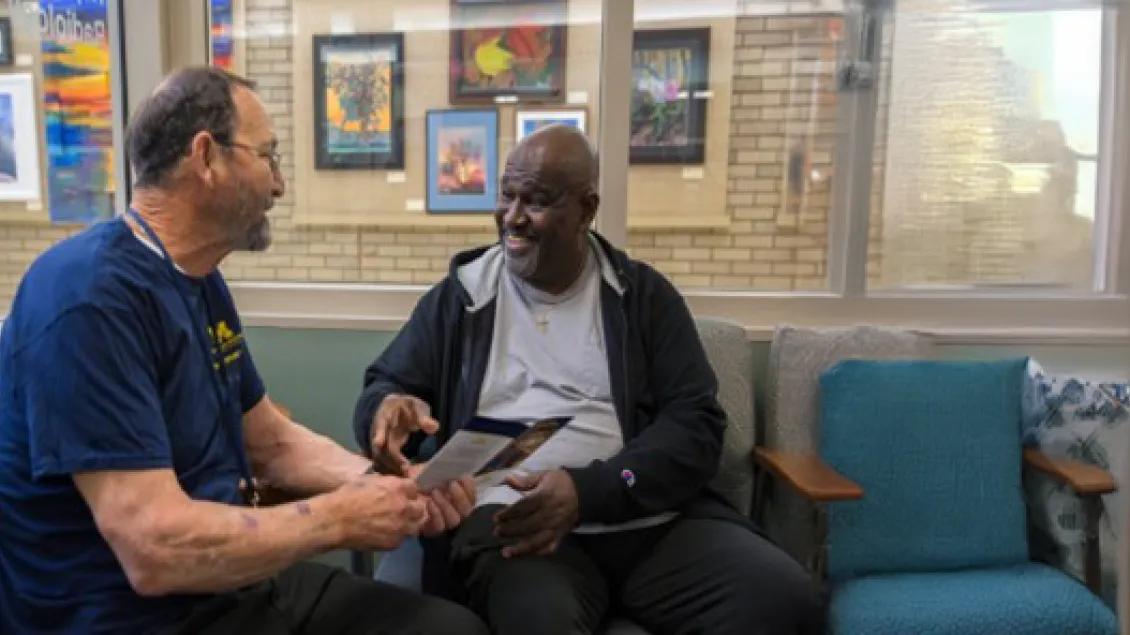 Two mentors from OPE seated in a lounge area and talking with each other.