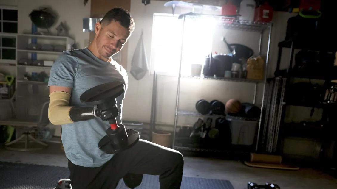 Man lifting a weight using his prosthetic hand in a garage gym
