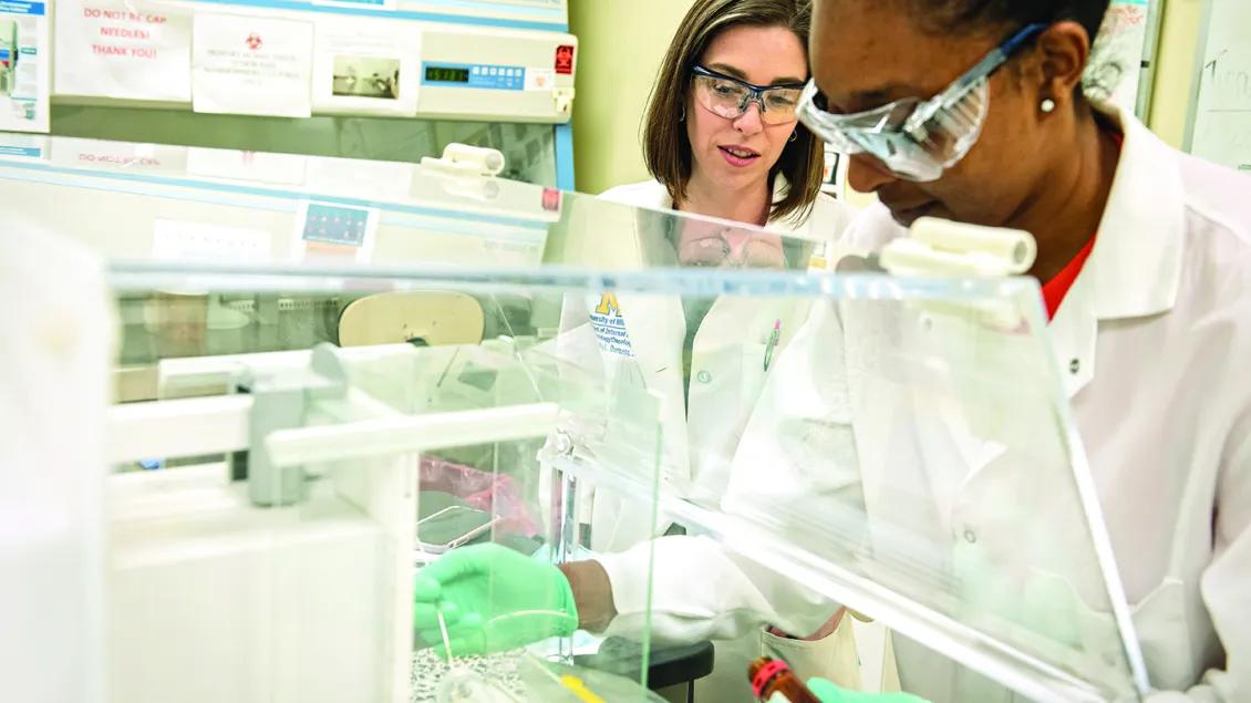 Monika Burness, M.D., and another medical professional working together in a laboratory setting.