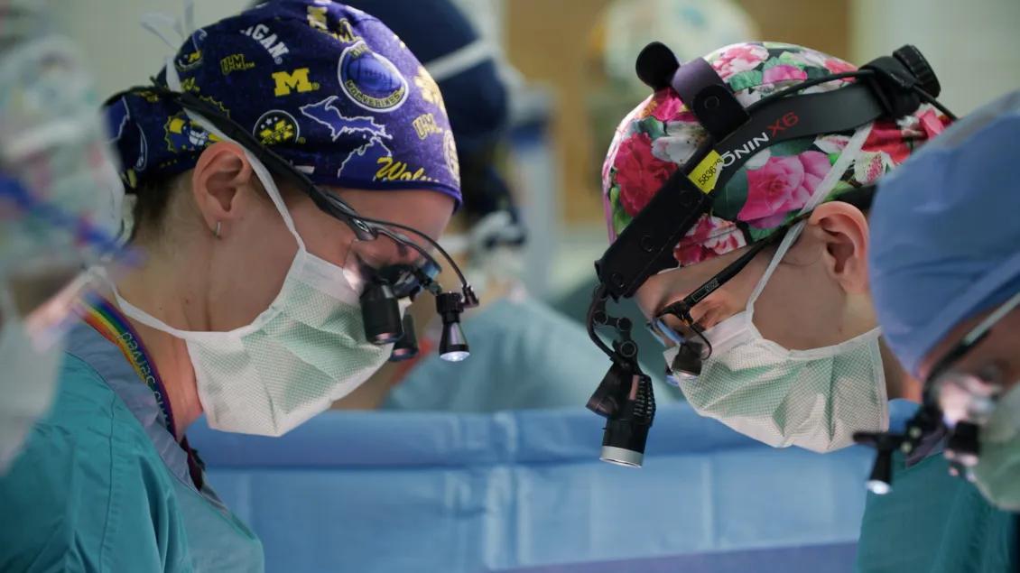 Two female surgeons wearing loupes and masks