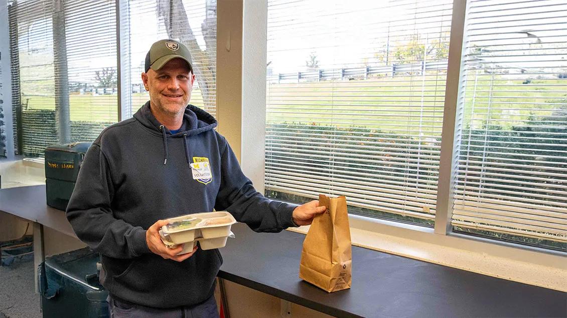 A volunteer for Meals of Wheels holds a bag of food. 